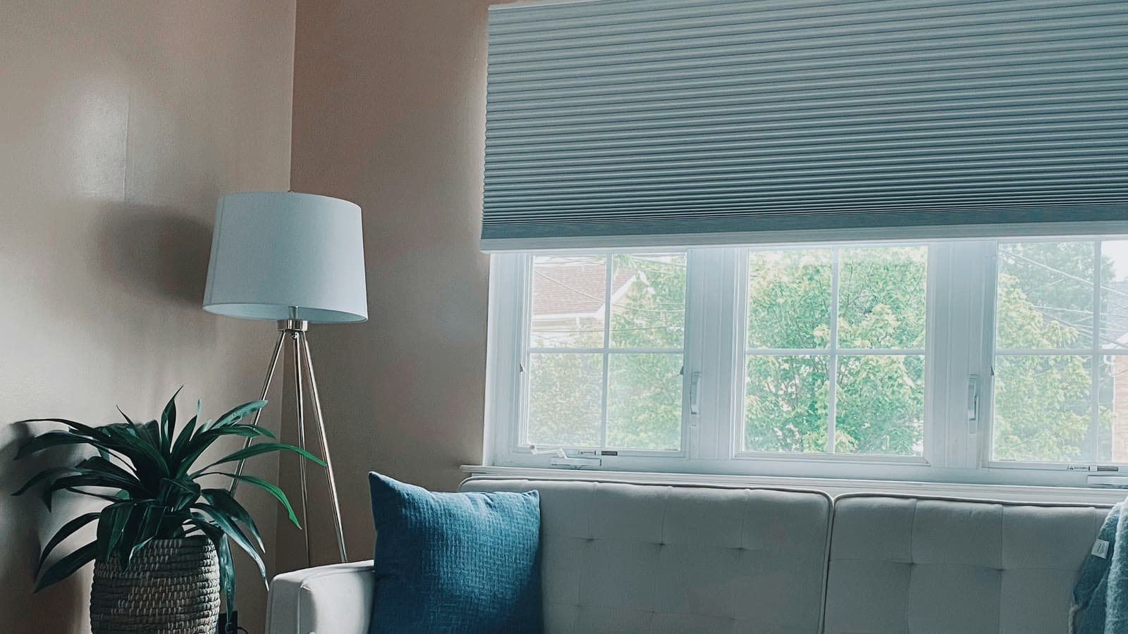 Blue grey cellular shade half lowered over a three pane window